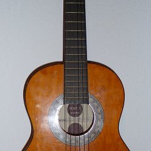 Renata Konzertgitarre

Damit fing alles an. Das Ding hatte ich mit 12 unterm Weihnachtsbaum und hab mich erstmal gar nicht dafür interessiert. Als ich dann gemerkt habe, dass es doch coole Gitarren gibt (nämlich elektrische ;-) ), find ich dann doch an, mich damit zu beschäftigen, hab das beiliegende Lehrbüchlein durchgearbeitet, geübt und einen selbstgebastelten Pickup aufgeklebt und über mein verzerrendes Transistorradio gerockt. So war es wirklich!

Das Teil ist der letzte Schrott. Das Griffbrett ist aus dem selben Abfallholz wie der Rest und nur schwarz angemalt. Man bekommt auch heute noch etwas schwarze Finger, wenn man zu sehr schwitzt. Ich nehme sie immer auf Segeltörns mit. Leider ist sie bis heute noch nicht über Bord gegangen...