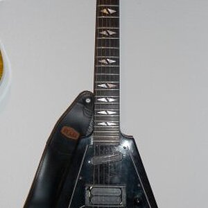 Gibson V90

Ich weiss noch wie ich damals, meiner schrottigen Hohner ST Special entwachsen, auf der Suche nach meiner ersten "richtigen" E-Gitarre war und in einem Gitarrenladen in Frankfurt so eine Flying V in der Hand hatte. Das Teil hatte mich einfach umgehauen. Leider konnte ich mir so ein Ding überhaupt nicht im entferntesten leisten, aber seitdem musste ich eine Flying V haben. Unbedingt! Und hab dann letztlich eine gebrauchte ´72 Gibson Flying V gekauft, die in einem erbärmlichen Zustand war.
Naja, als dieses Ding vor ein paar Jahren auf eBay zum Verkauf stand, musste ich sie natürlich haben! Sie klingt auch für meinen Geschmack heute immernoch super! Sie hat nur zwei Probleme: sie ist sauschwer und eigentlich total kopflastig. Daher hab ich mir erlaubt, einen kleinen Ausleger hinten anzuschrauben, um einen günstigeren Punkt für die Gurtbefestigung zu schaffen. Deshalb sieht das so komisch aus mit dem Gurt da. ;-) Aber es wirkt!

Mahagonie-Korpus, Ahornhals (!), Setneck, Ebenholz Griffbrett, Pickups und Hardware original.