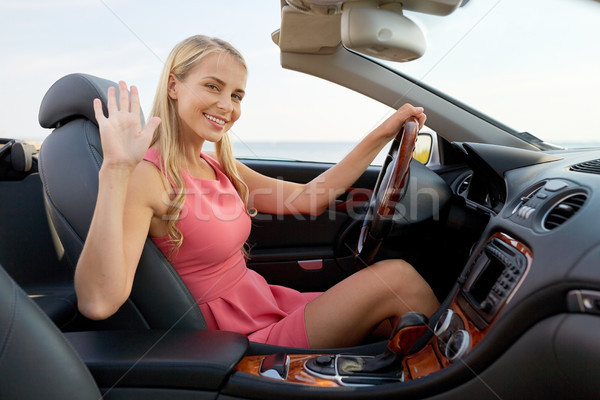 9150425_stock-photo-happy-young-woman-in-convertible-car-waving-hand.jpg